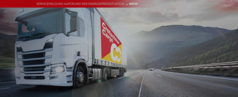 Lkw von Cretschmar Cargo auf einer Landstraße mit Bergen im Hintergrund, symbolisiert den Transport und die Logistikbranche.